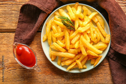 Plate with tasty french fries and ketchup on wooden background