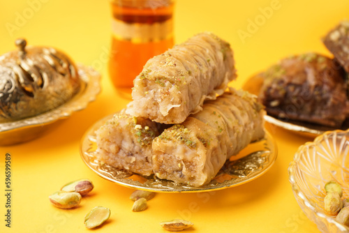 Plate with tasty baklava on yellow background, closeup