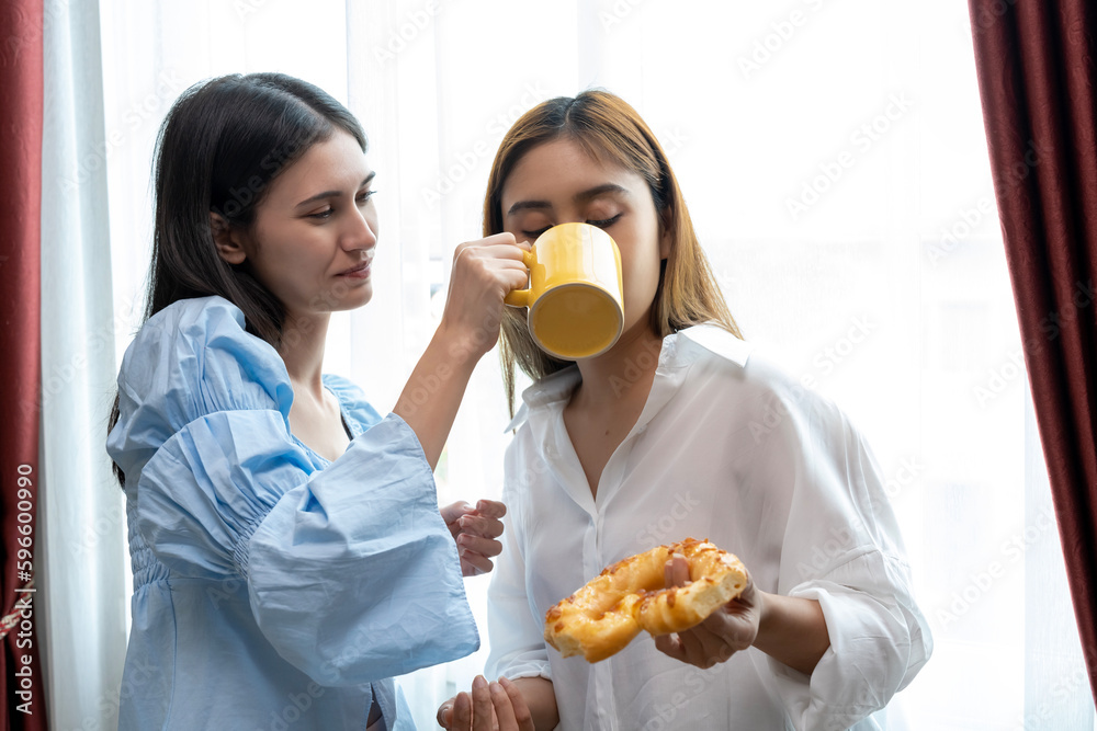Happy moment of Two pretty women drink coffee and talk together in kitchen
