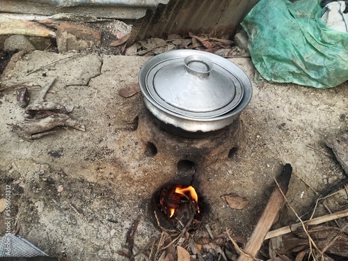 Rural kitchen. Traditional stoves used by residents in rural India, made of clay, fueled with wood, Cooking Food On Soil Stove With Dry Leafs And Wood In Village photo