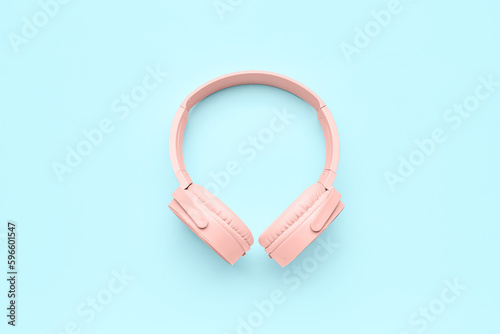 Modern pink headphones on blue background