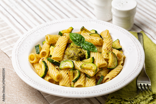 Plate of vegan tubular pasta dish, pistachio pesto rigatoni with zucchini. Italian food.