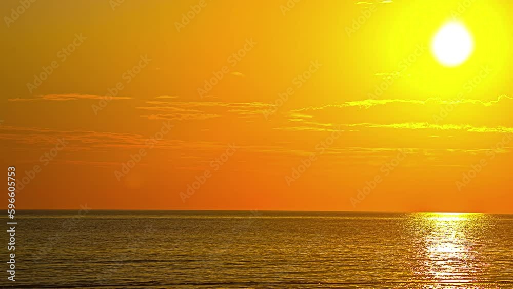 A large bright yellow sun turns the sky orange at sunrise over the ocean. Time Lapse A large bright yellow sun turns the sky orange at sunrise over the ocean. Time Lapse