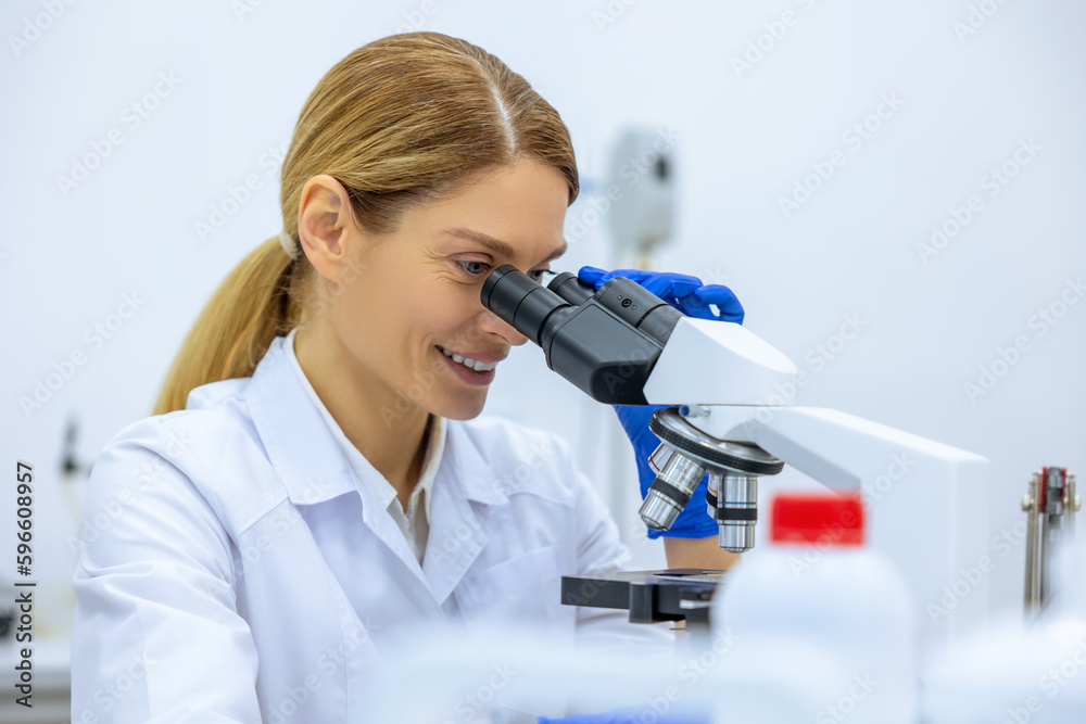 Scientist looking under microscope, doing analysis of test sample ambitious biotechnology specialist Scientist looking under microscope, doing analysis of test sample ambitious biotechnology specialist