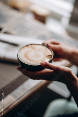a cup of cappuccino in the hands of a girl