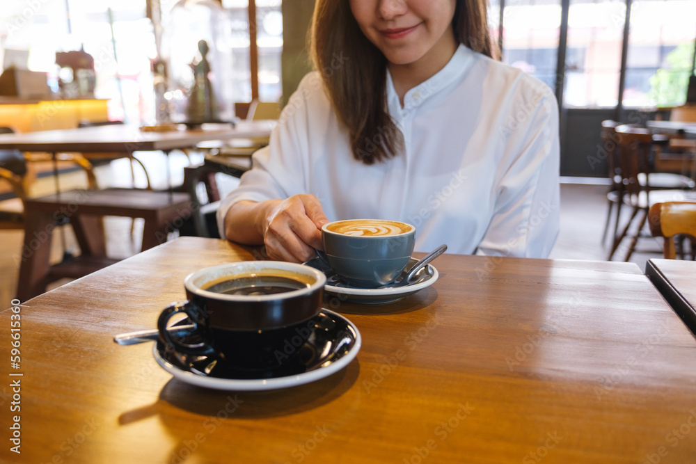 Closeup image of a woman holding and drinking coffee with friend in cafe