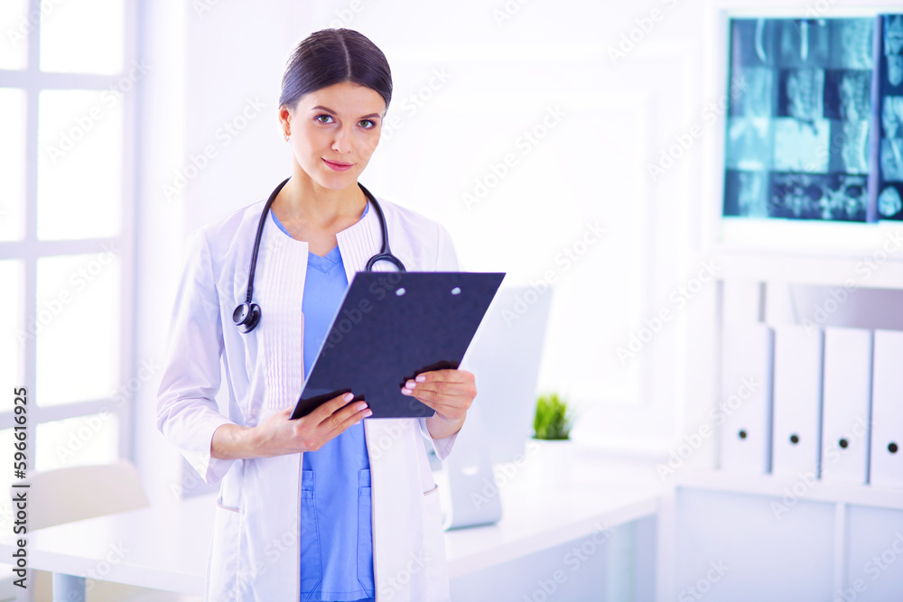Young smiling female doctor with stethoscope holding a folder at doctor's office Young smiling female doctor with stethoscope holding a folder at doctor's office