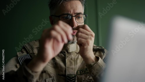 Soldier with glasses working with laptop in home. Everyday life of a military man in reserve. Work and communication online photo