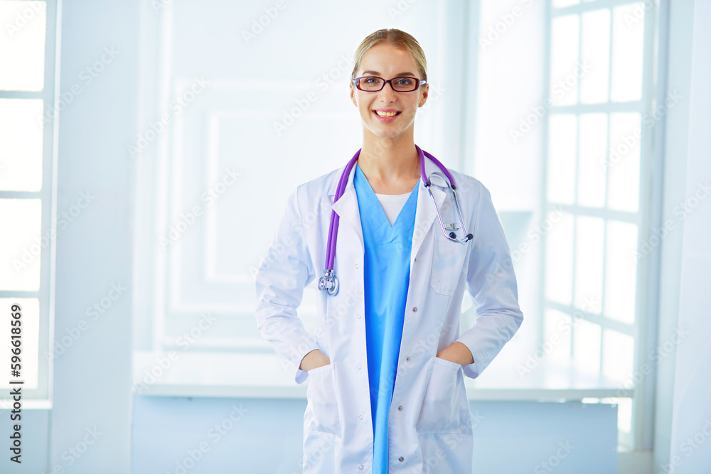 Young doctor woman standing near table, isolated on white backgrou. Young doctor woman standing near table, isolated on white backgrou.