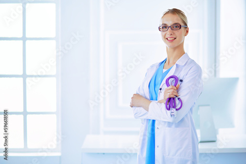 Cheerful happy doctor with crossed hands on blue background.