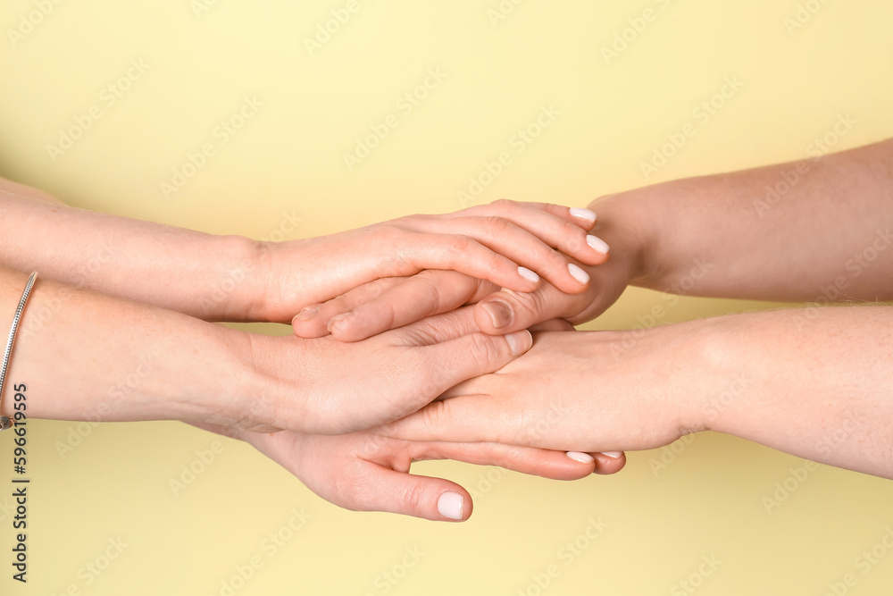 Women putting hands together on yellow background. Friendship concept Women putting hands together on yellow background. Friendship concept