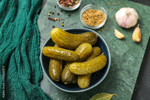 Bowl with tasty fermented cucumbers on dark grunge background