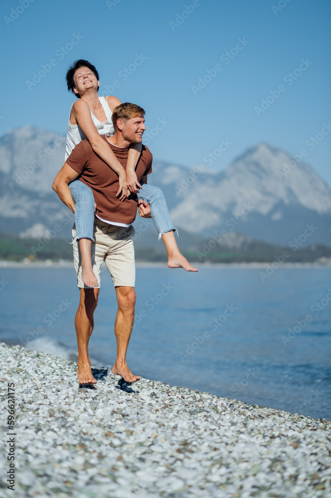 Middle aged couple in love having fun piggybacking. Mix national relationship.