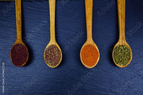 Spoons with oriental spices on a slate board. Top view