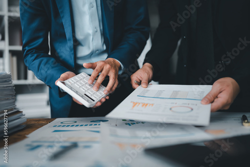 Accountant checking financial statement or counting by calculator income for tax form, Business woman sitting and working with colleague discussing the desk in office. Audit concept