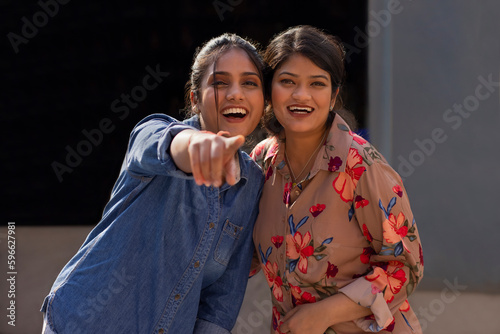 Portrait of two smiling women pointing