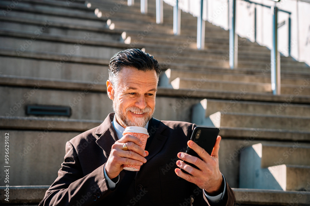 Cheerful adult man with smartphone and takeaway coffee on stairs Cheerful adult man with smartphone and takeaway coffee on stairs