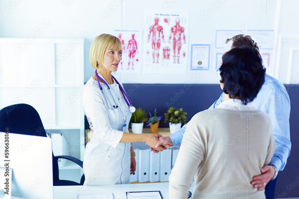 Fototapeta premium Female doctor handshaking a patient's hand and smiling.