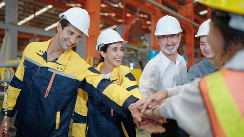 Team of factory workers standing putting their hand stacking together in industry factory. Unity and teamwork concept