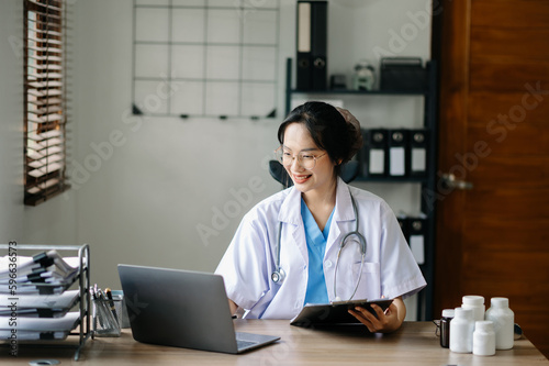 Asian smiling doctor or consultant sitting at a desk his neck looking at the camera.