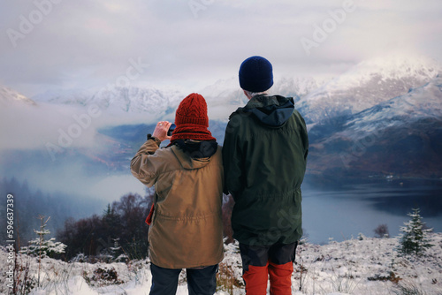 An elderly couple watching misty snowy mountains in winter from a distance