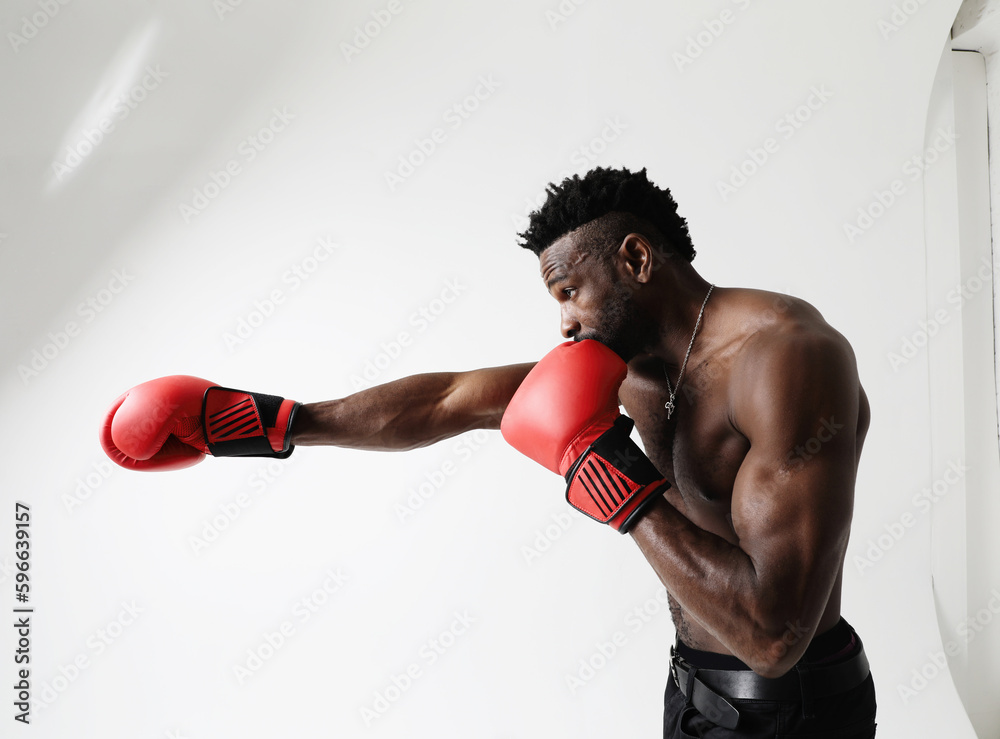 Athletic young man with good physique body condition boxing with red gloves. 