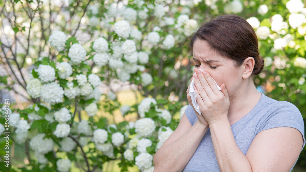 Caucasian woman suffers from allergies and sneezes while walking in the park. Caucasian woman suffers from allergies and sneezes while walking in the park.