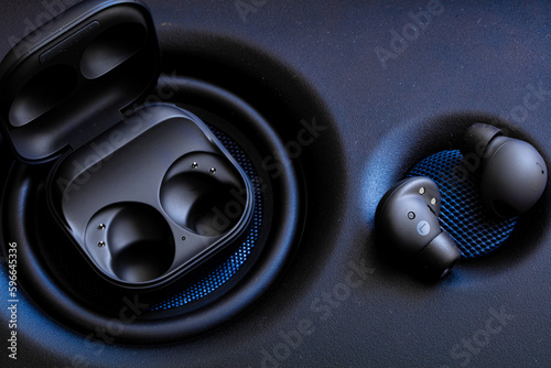 black wireless earpone buds on speakers background