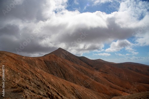Detalle de una impresionante montaña rocosa de origen volcánico con una cumbre muy puntiaguda en medio de un paisaje desértico en la turística isla de Fuerteventura en las Islas Canarias.