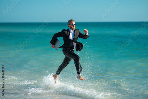 Excited millennial hispanic business man in suit on sea. Summer vacation, business on sea beach. 40s business man on summer business travel. Dream for summer vacations office workers.