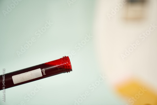 A transparent test tube for tests at an angle with red drop of blood on a light background. Selective focus. With a space to copy. High quality photo