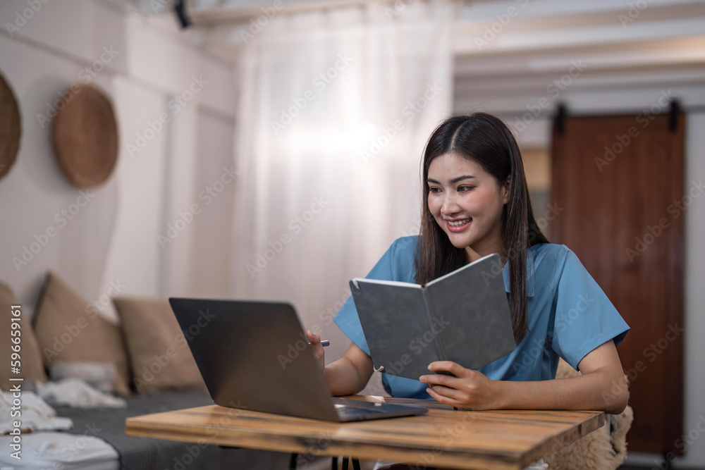 Beautiful asian woman relaxing using laptop computer while sitting on table with notepad, concept at home