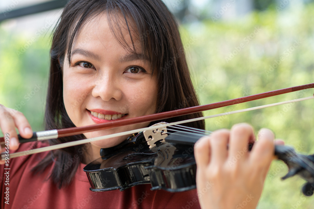 An attractive woman learning musician plays the violin at home. Composer creating songs with string instruments. Dreamy violinist fingers pressing strings on violin An attractive woman learning musician plays the violin at home. Composer creating songs with string instruments. Dreamy violinist fingers pressing strings on violin