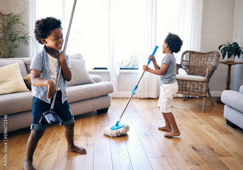 Obraz na plátně Two mixed race little boys playing with a mop and broom in the lounge at home