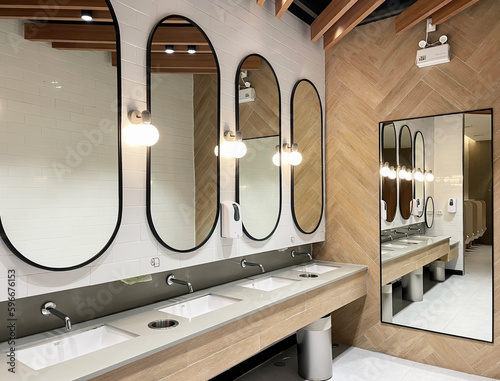 Minimal style and modern beautiful interior design of public restroom with row of mirrors, sinks with faucets, bright decorating light, ceramic wall fllor and emergency light.