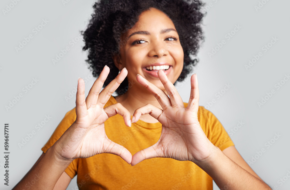 Put some love into it. Shot of a young woman forming a heart shape while posing against a grey background. Put some love into it. Shot of a young woman forming a heart shape while posing against a grey background.