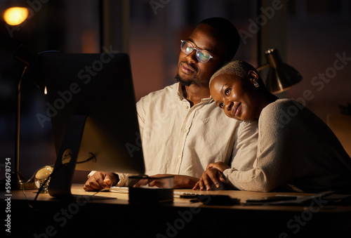The romance is brewing between them. Shot of two affectionate businesspeople working together on a computer in an office at night.