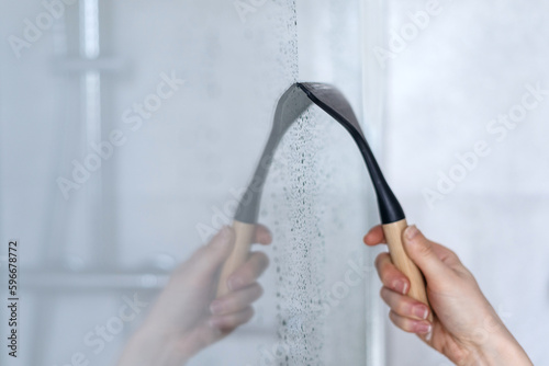 Glass squeegee erase drops and dirt on shower partition photo