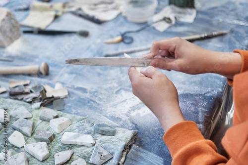 Hands of child processing ornamental stone with file at stone carving masterclass.
