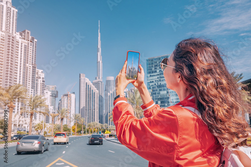 Obraz na płótnie Tourist happy girl taking photos for her travel blog, in Dubai downtown district against background of the Burj Khalifa highest skyscraper w salonie