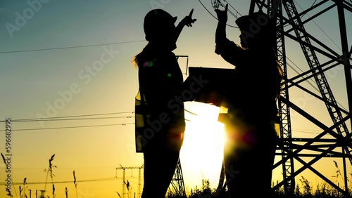 silhouette engineer working laptop. electric tower. computer technology. business handshake deal. energy concept. electrical engineer sunset. teamwork. energy people group. teamwork high voltage