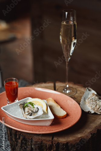 oyster with lemon on ice, next to spicy sauce and champagne
