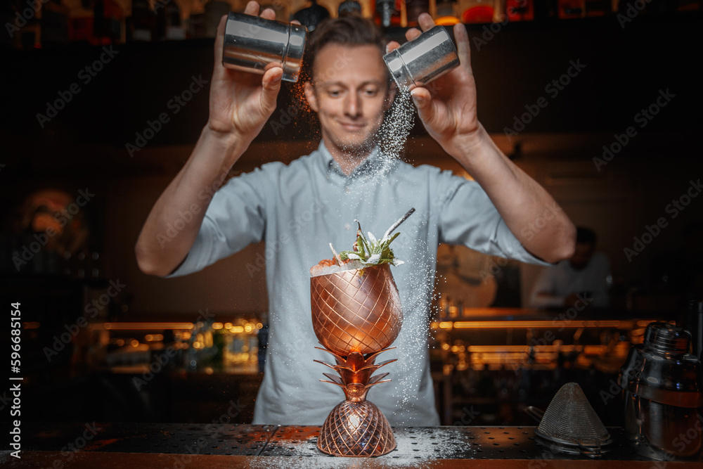 male bartender prepares a cocktail and sprinkles with powder