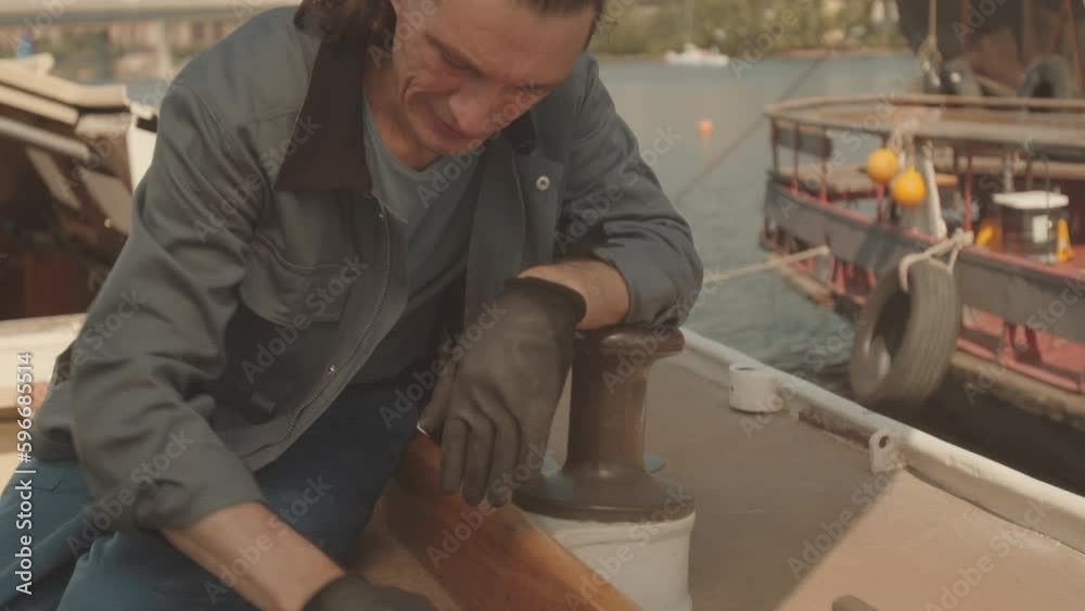 Waist up portrait of Caucasian man looking at camera while polishing wood on yacht deck Waist up portrait of Caucasian man looking at camera while polishing wood on yacht deck