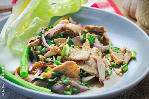 Sliced grilled beef salad, Isaan food in Thailand, local food in Thailand. Served with long beans and lettuce On a gray plate served in a Thai restaurant.