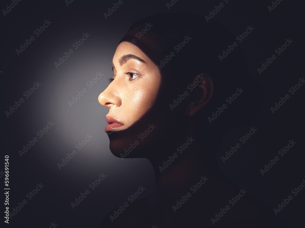 Lets shine the spotlight on skincare. Studio shot of a beautiful young woman posing with light beam against her face.
