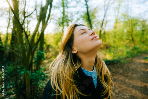 Attractive caucasian woman breathe fresh air , enjoying springtime on a sunset in natural parkland