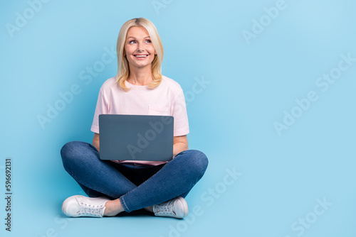 Full length photo of satisfied retired person t-shirt pants sitting directing look at sale empty space isolated on blue color background