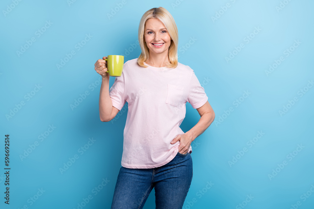 Portrait of friendly optimistic senior woman with bob hairstyle wear white t-shirt hold mug of coffee isolated on blue color background