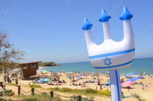 Concept: sea holidays in Israel. Resorts of the Holy Land. Trident with the Yerb of Isael the Star of David on the background of the beach and the sea. Space for text photo